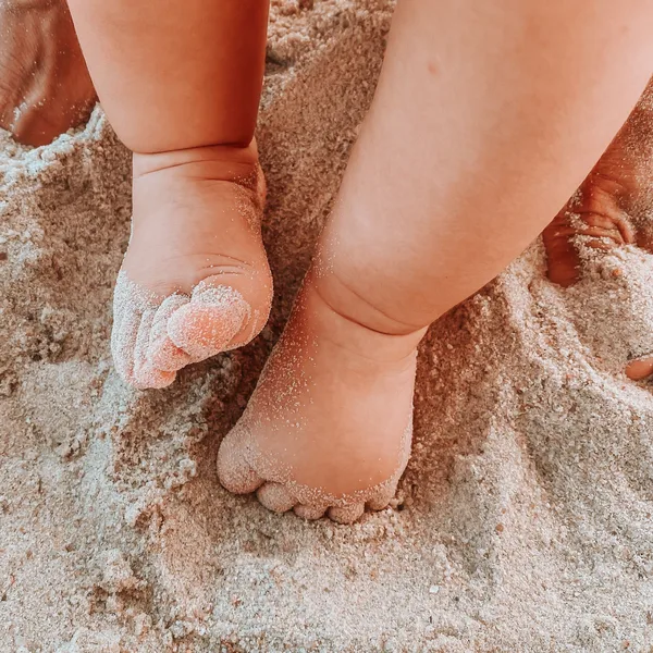 Small baby feet standing in soft sand